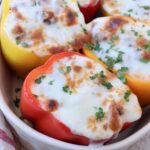 stuffed peppers topped with melted mozzarella cheese in casserole dish