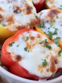 stuffed peppers topped with melted mozzarella cheese in casserole dish
