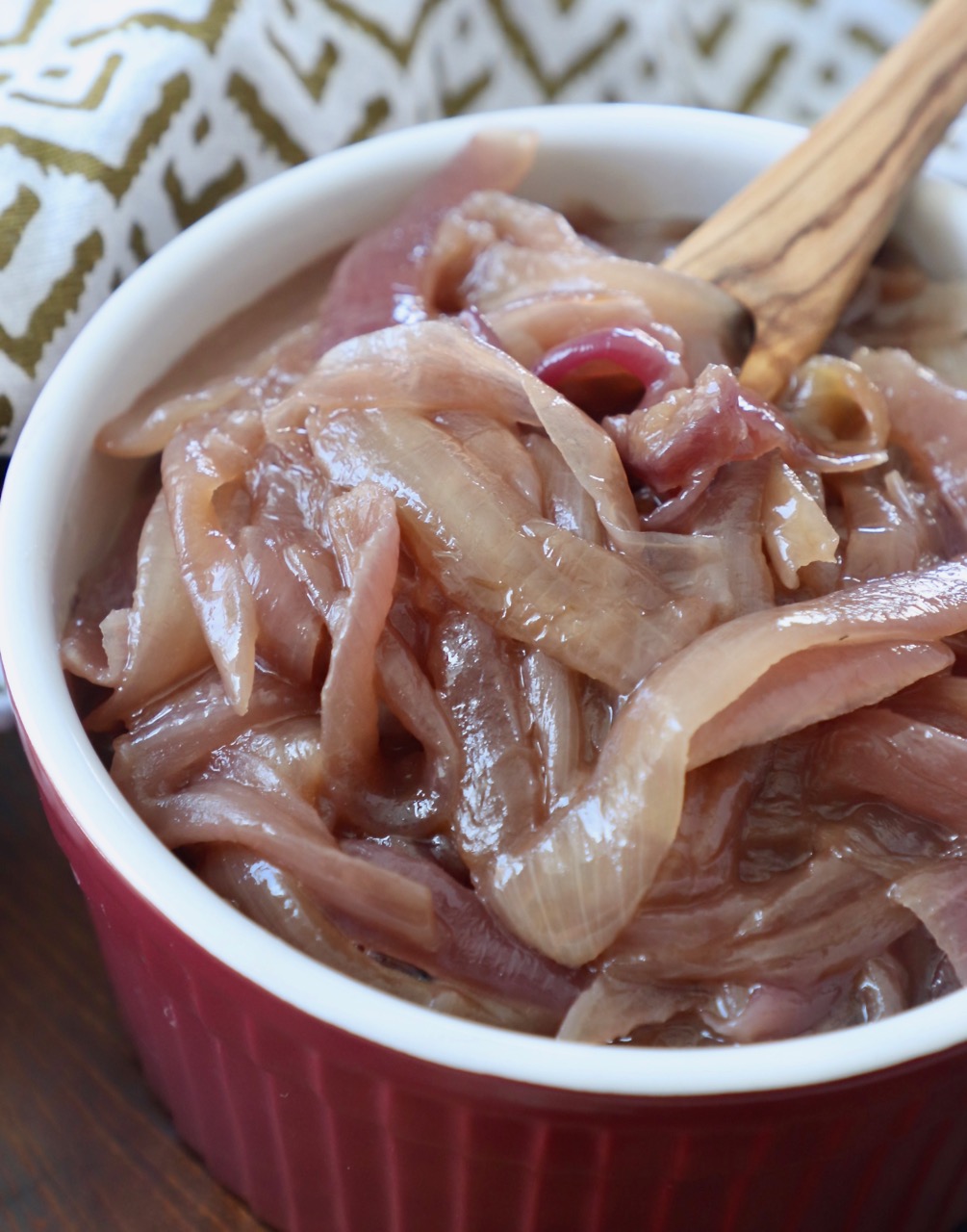 caramelized onions in red bowl with wooden fork