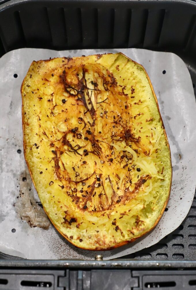 cooked spaghetti squash half in air fryer basket