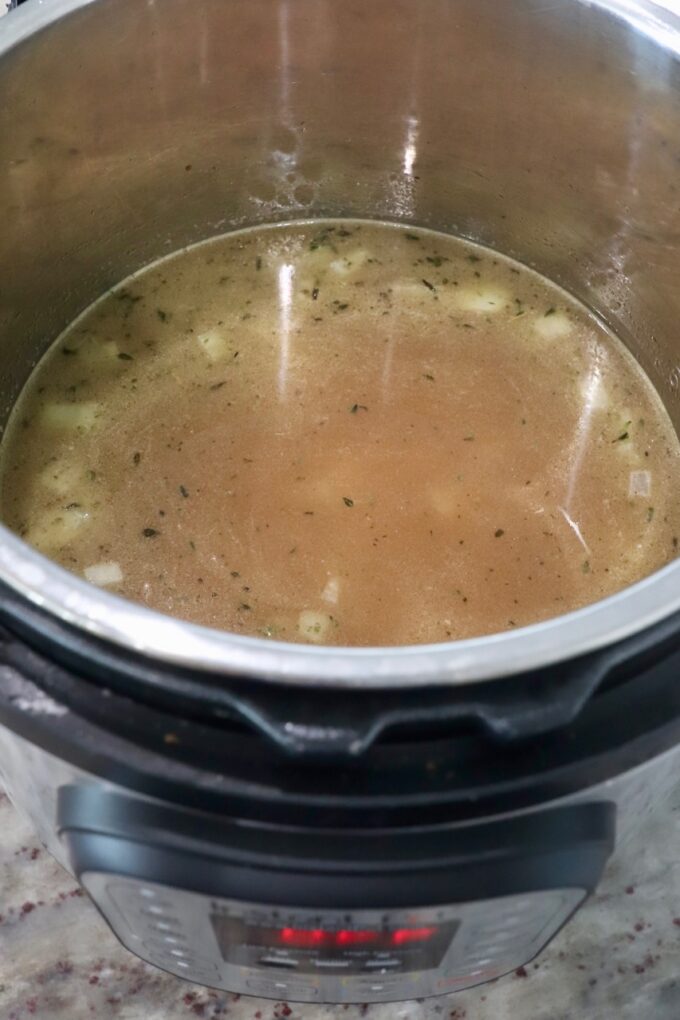 chicken broth in Instant Pot with rice and onions
