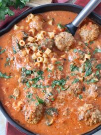 Italian pasta and meatball soup in skillet with serving spoon