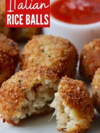 cooked Italian rice balls on plate cut in half with bowl or marinara sauce