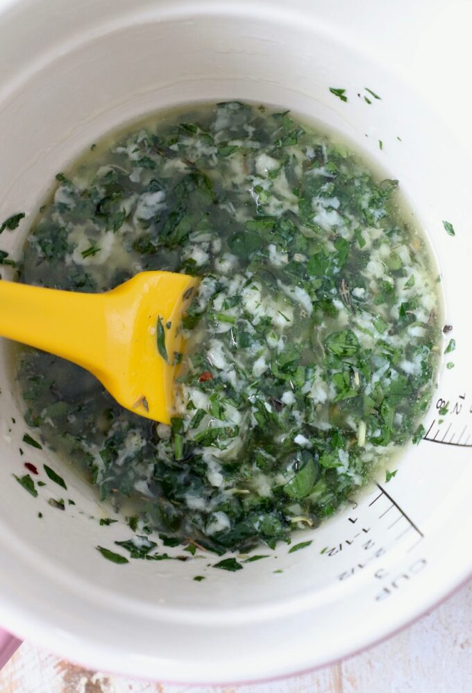melted butter with herbs and seasonings in a bowl with a spatula