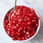 pomegranate arils in bowl with spoon
