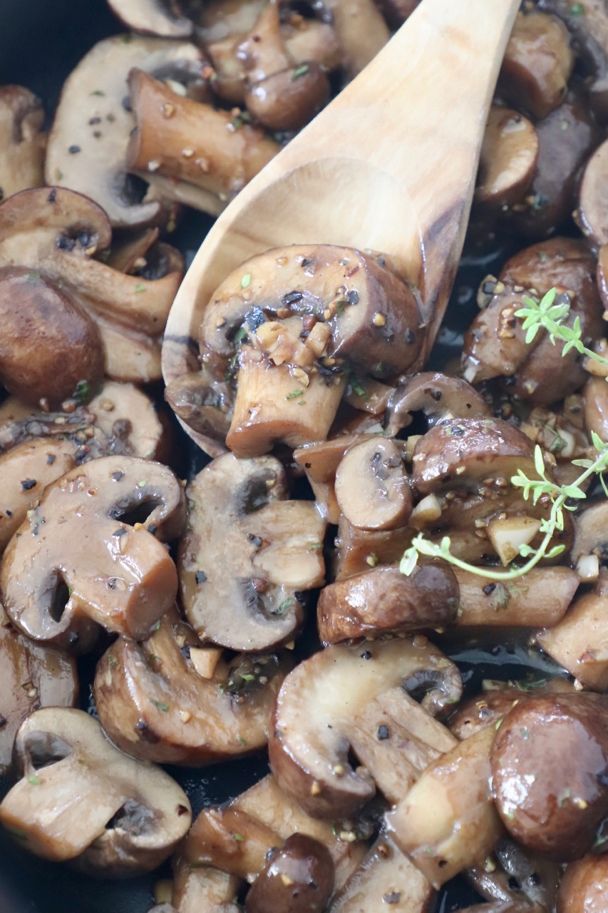 sauteed mushrooms in skillet with wooden spoon