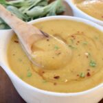 acorn squash soup in bowl with wooden spoon