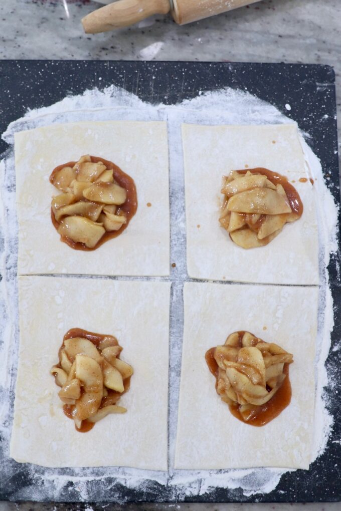 puff pastry sheet of dough on cutting board, topped with apple pie filling