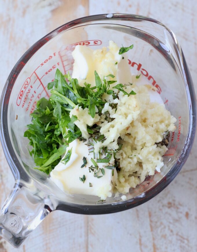 butter, garlic and herbs in glass mixing bowl