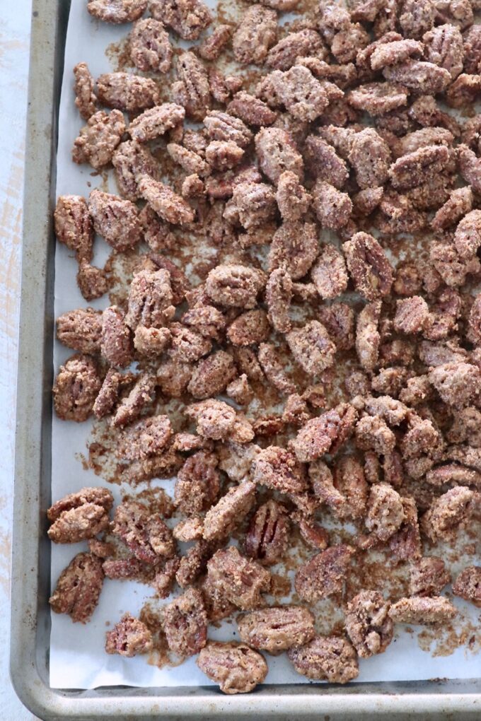 baked candied pecans spread out on baking sheet