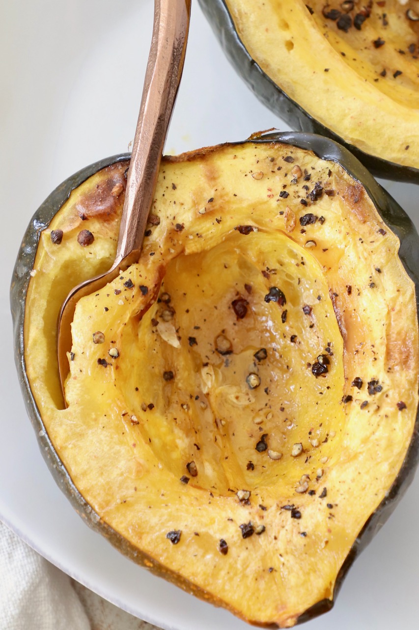 roasted acorn squash cut in half on plate with fork