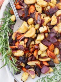 roasted carrots and parsnips on plate with large fork and fresh rosemary