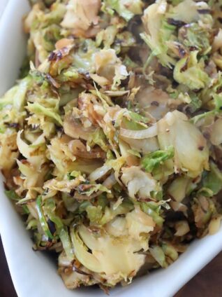 cooked shaved brussels sprouts in white serving dish