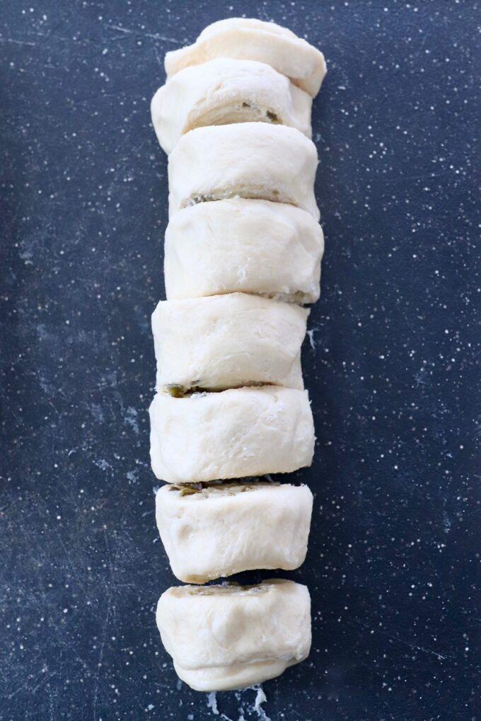 crescent roll dough rolled up and sliced on cutting board