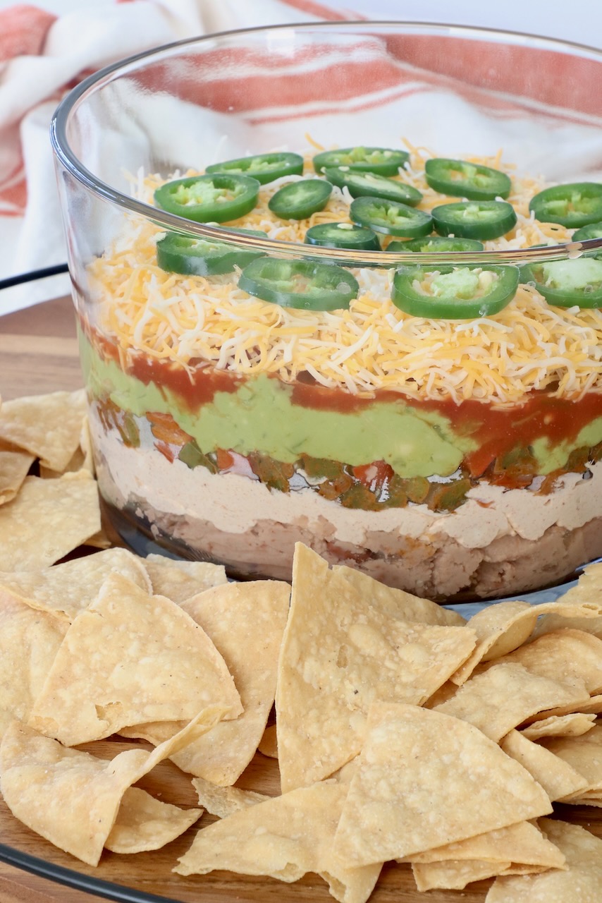 seven layer dip in glass trifle on serving tray with tortilla chips