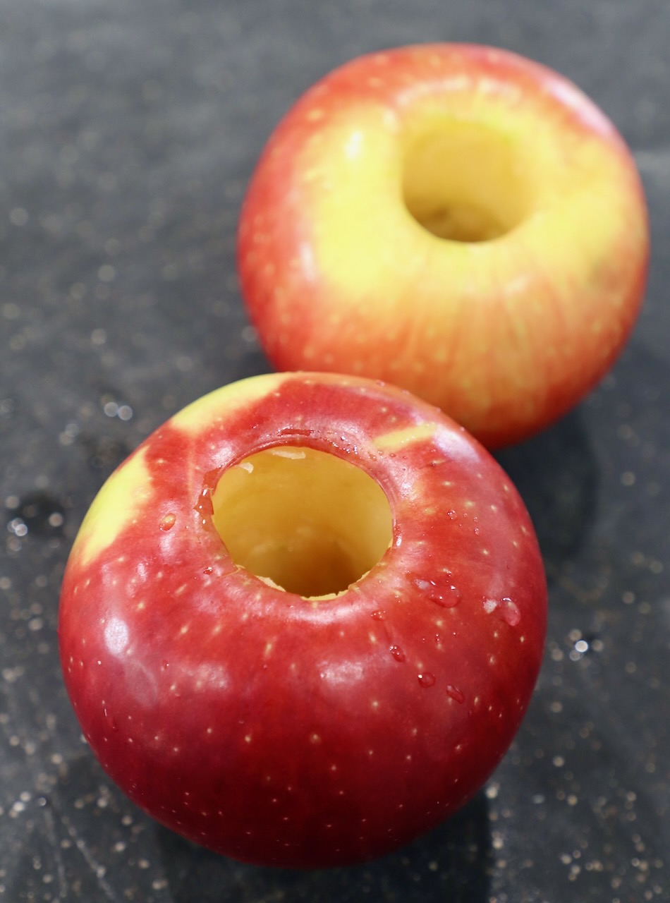two cored apples on cutting board 