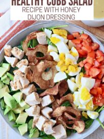 cobb salad in bowl with honey dijon dressing in bowl on the side