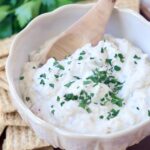 creamy garlic dip in bowl with wooden spoon
