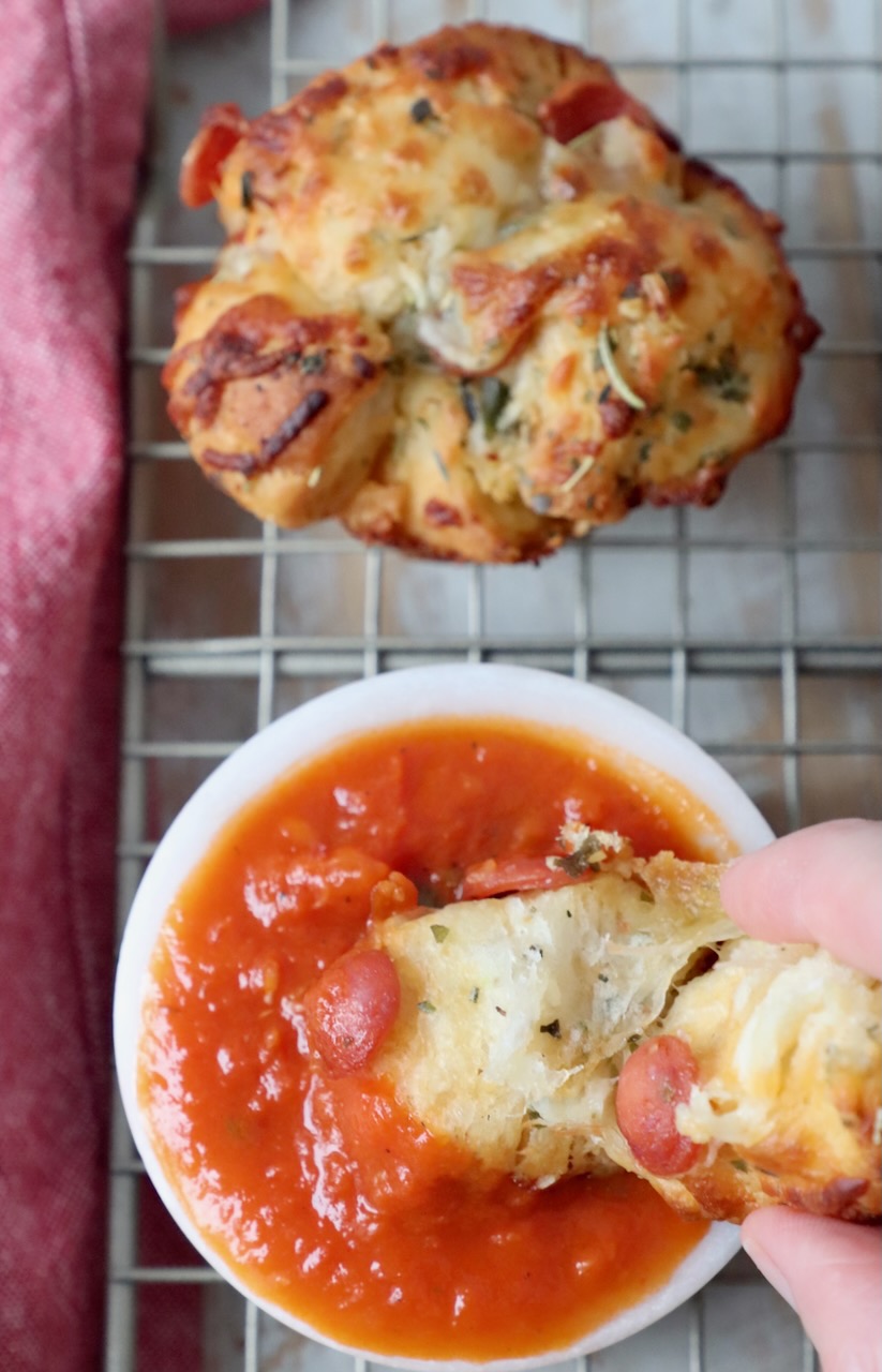 hand dipping pizza roll into bowl or marinara sauce