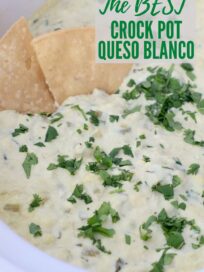 white queso dip in crock pot topped with fresh cilantro, with tortilla chips in the dip