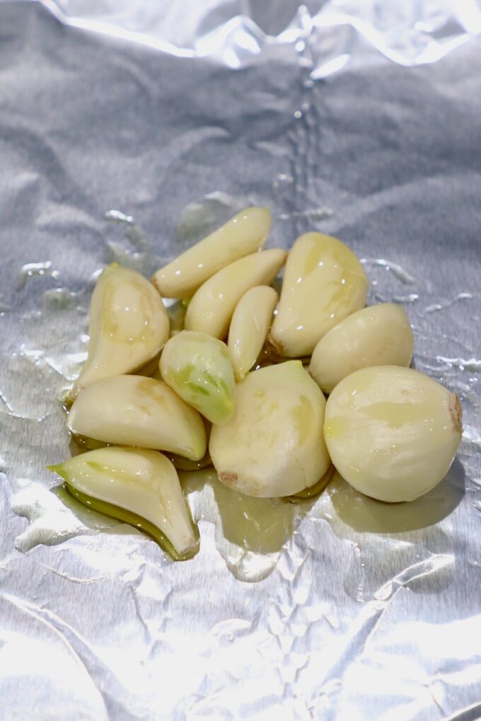 peeled garlic cloves on foil tossed in oil