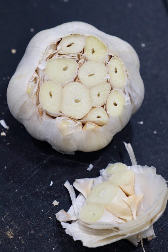 head of garlic with the top cut off on cutting board