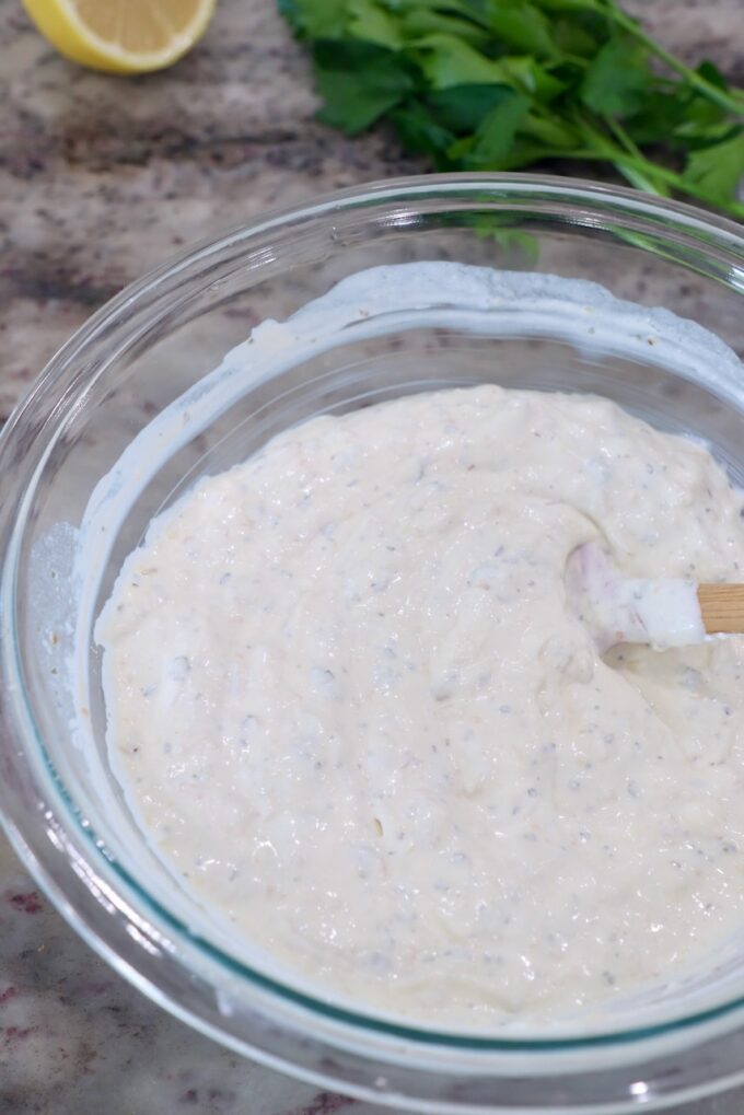 roasted garlic dip in glass bowl with spatula