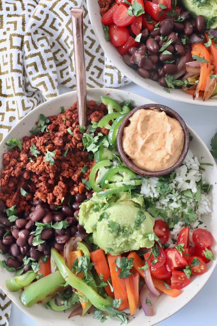 cooked vegetables, soy chorizo, beans, guacamole and rice in bowl with fork