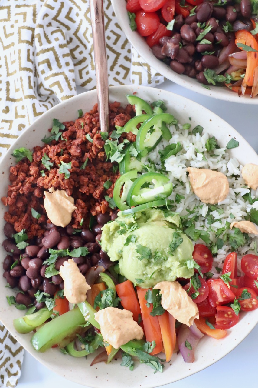 cooked rice, vegetables and soy chorizo in bowl with guacamole and chipotle sauce