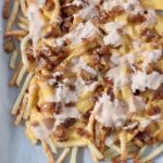 cooked fries covered in cheese, onions and sauce