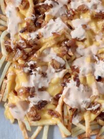 cooked fries covered in cheese, onions and sauce