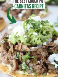 tostada topped with cooked carnitas pork, guacamole and crumbled cotija cheese