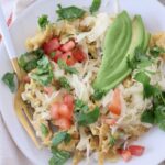 migas on plate with fork, topped with sliced avocado