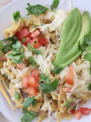 migas on plate with fork, topped with sliced avocado