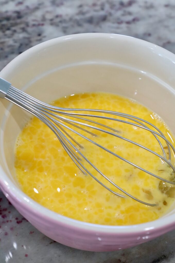 whisked eggs in mixing bowl with large whisk