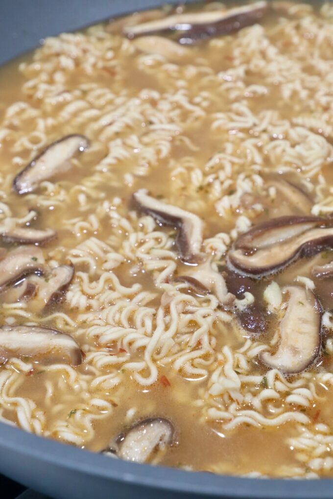 ramen noodles in broth with mushrooms in large wok