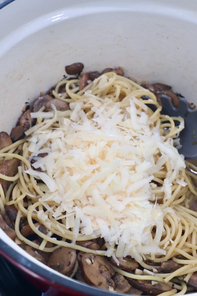 sliced mushrooms in pot with parmesan cheese and cooked spaghetti