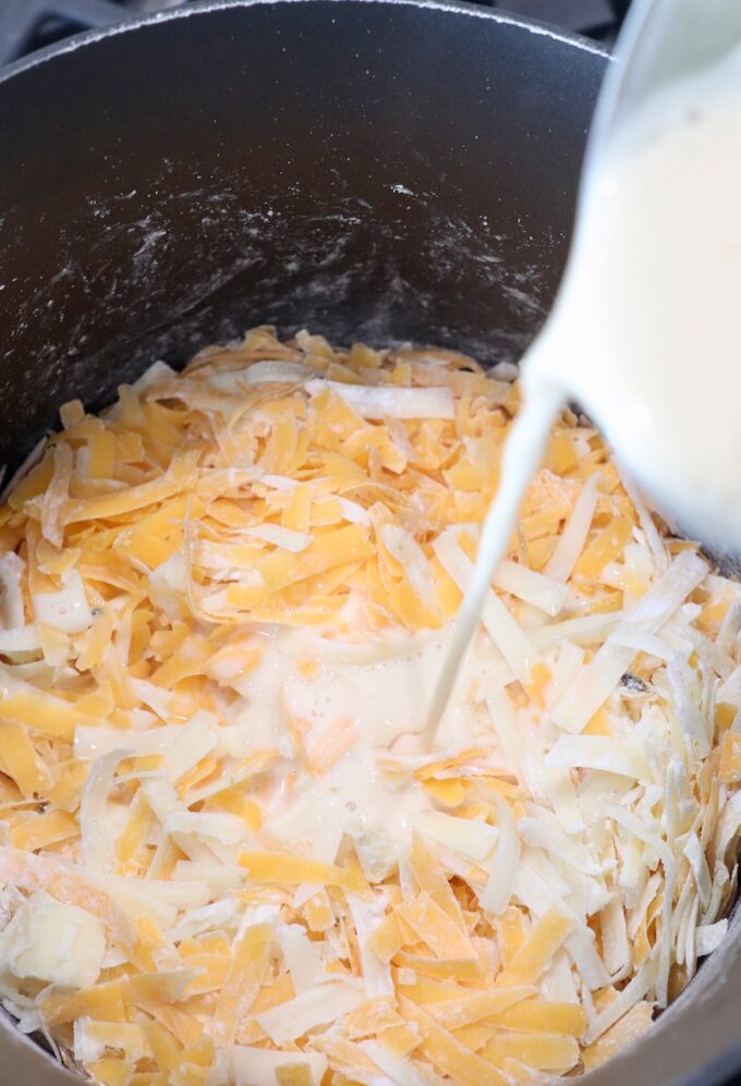 milk being poured into sauce pan of shredded cheese