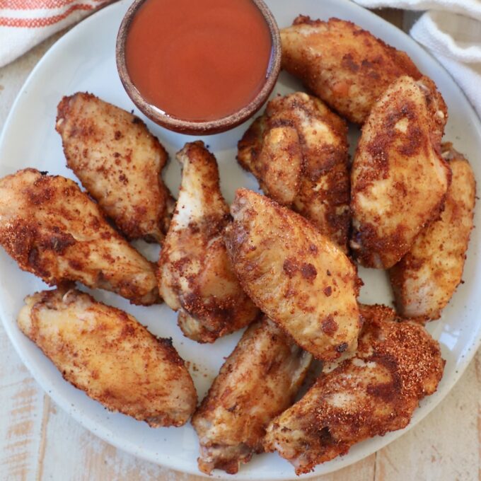 cooked chicken wings on plate with small bowl of buffalo sauce