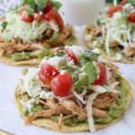 shredded chicken on tostadas with guacamole and tomatoes