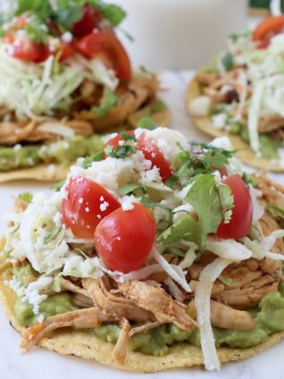 shredded chicken on tostadas with guacamole and tomatoes