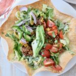 taco salad in tortilla shell on plate