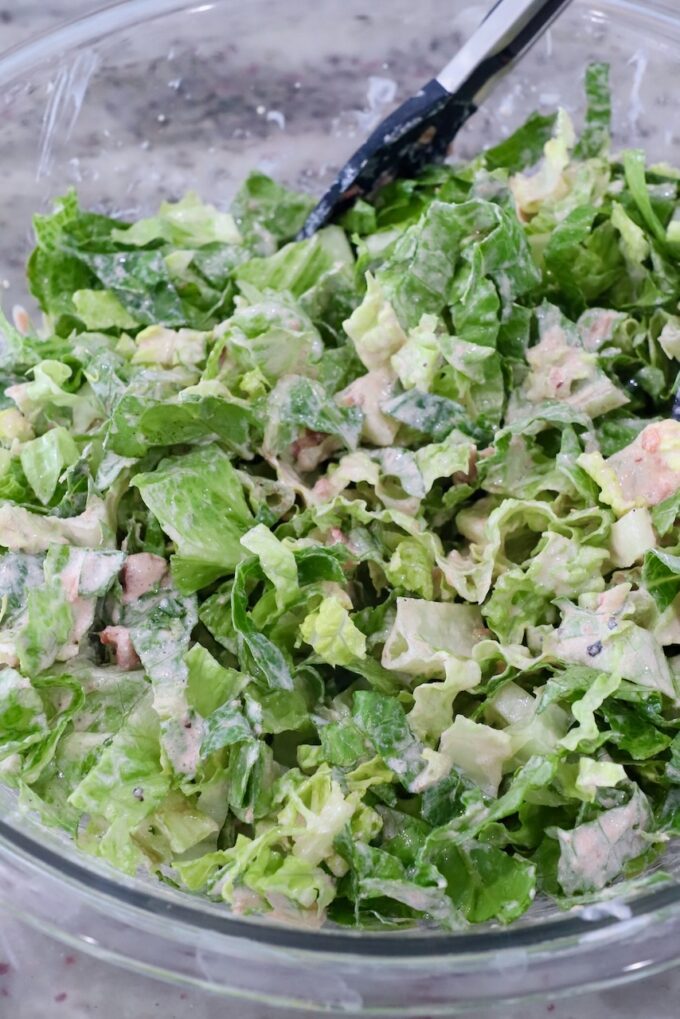 shredded lettuce tossed with salad dressing in large glass bowl