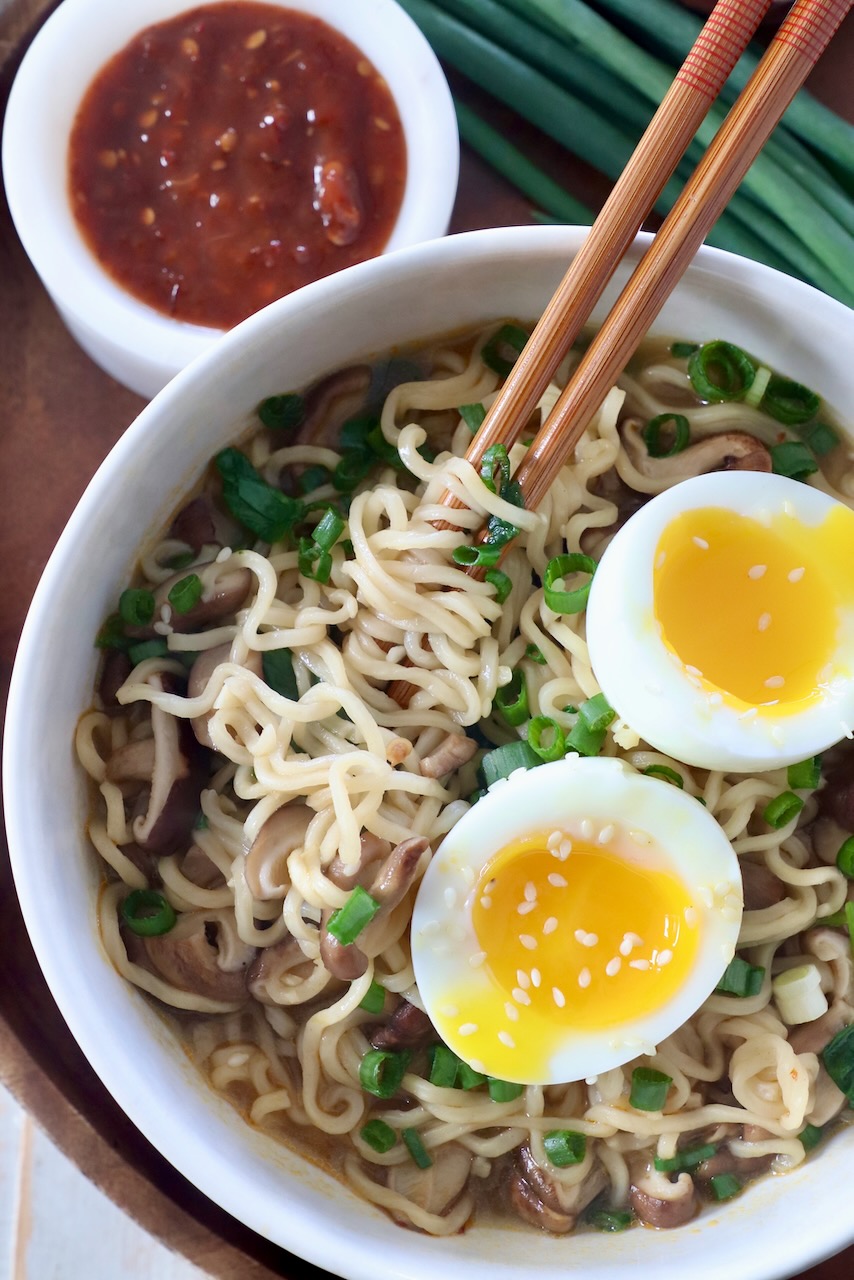 cooked ramen noodle soup in bowl with chopsticks and soft boiled egg