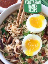 ramen noodle soup in bowl with chopsticks, topped with a soft boiled egg, cut in half