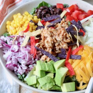 salad in bowl topped with shredded bbq chicken and vegetables