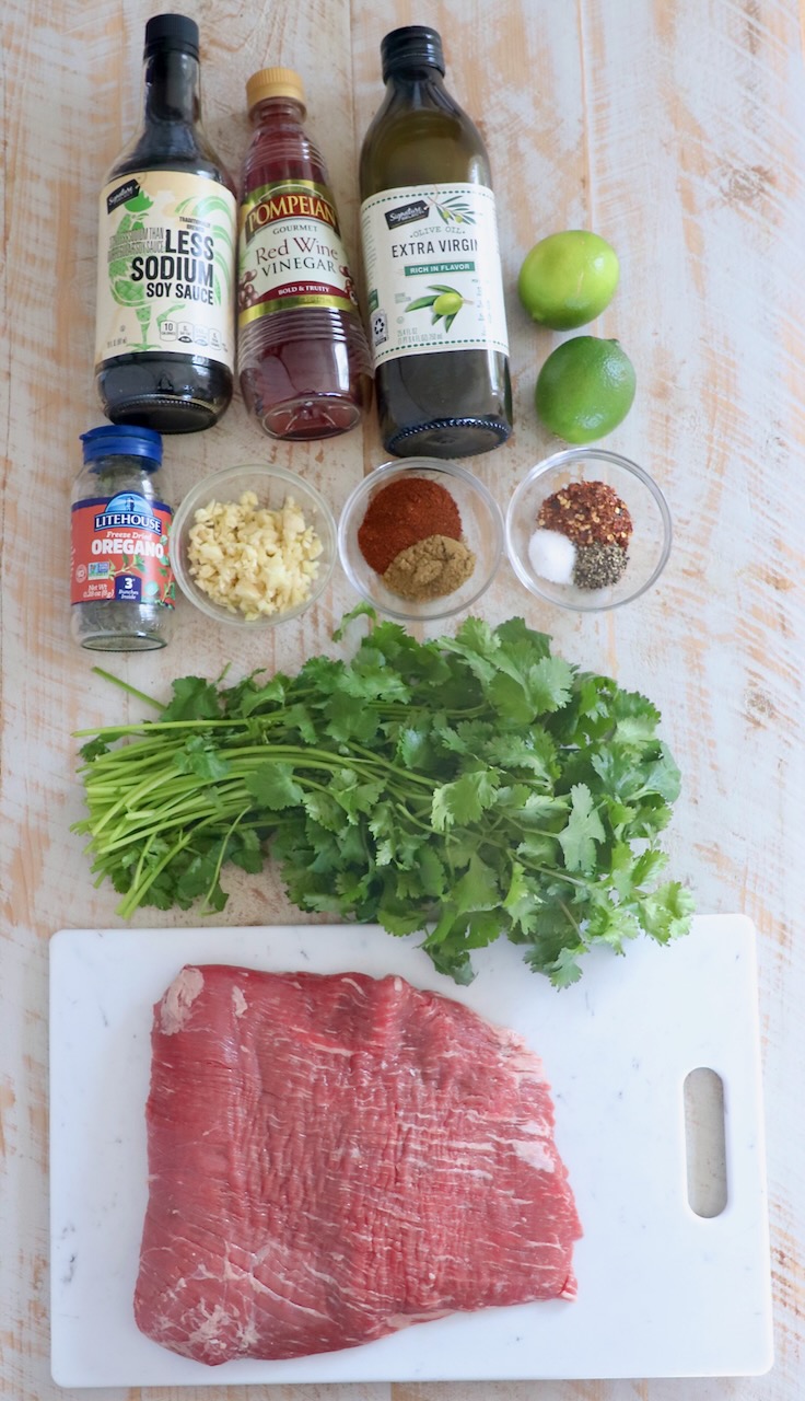 flank steak taco ingredients on white wood board