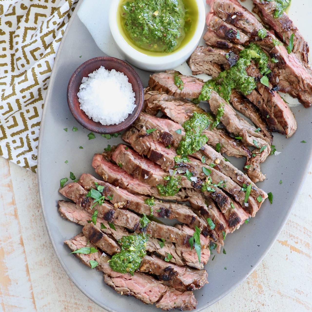 sliced skirt steak on plate topped with chimichurri sauce
