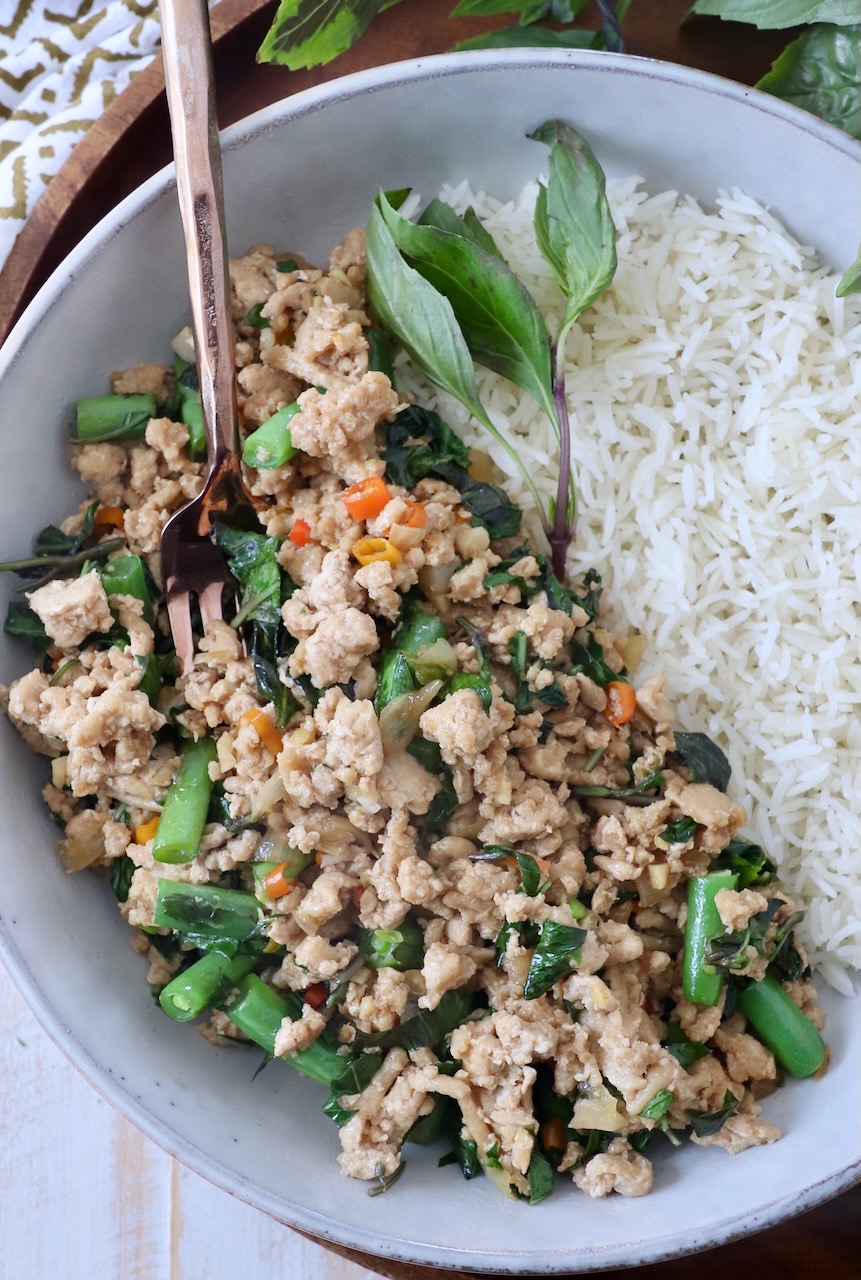 thai basil chicken in bowl with white rice and fork