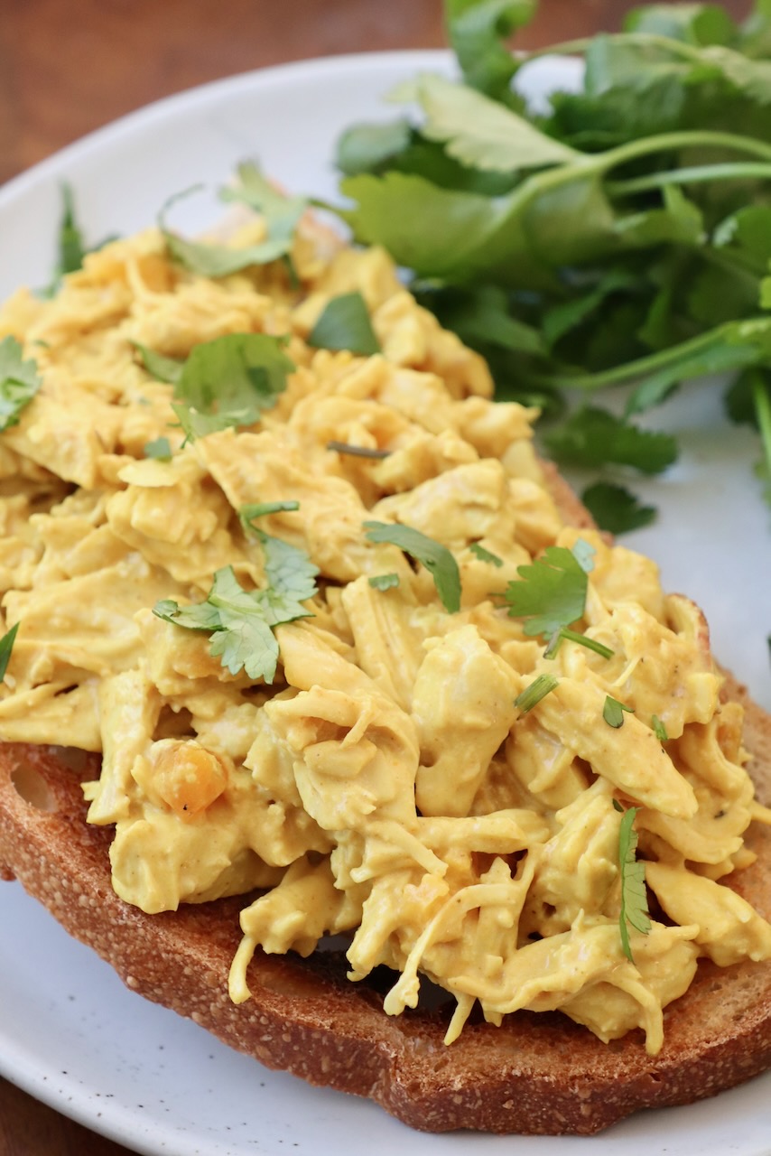 coronation chicken on toast, on white plate with cilantro